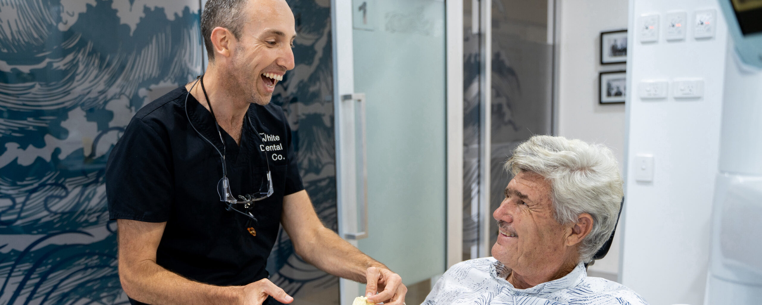 Dr Nick and a patient in the treatment room during an appointment. Both are laughing at a shared joke.
