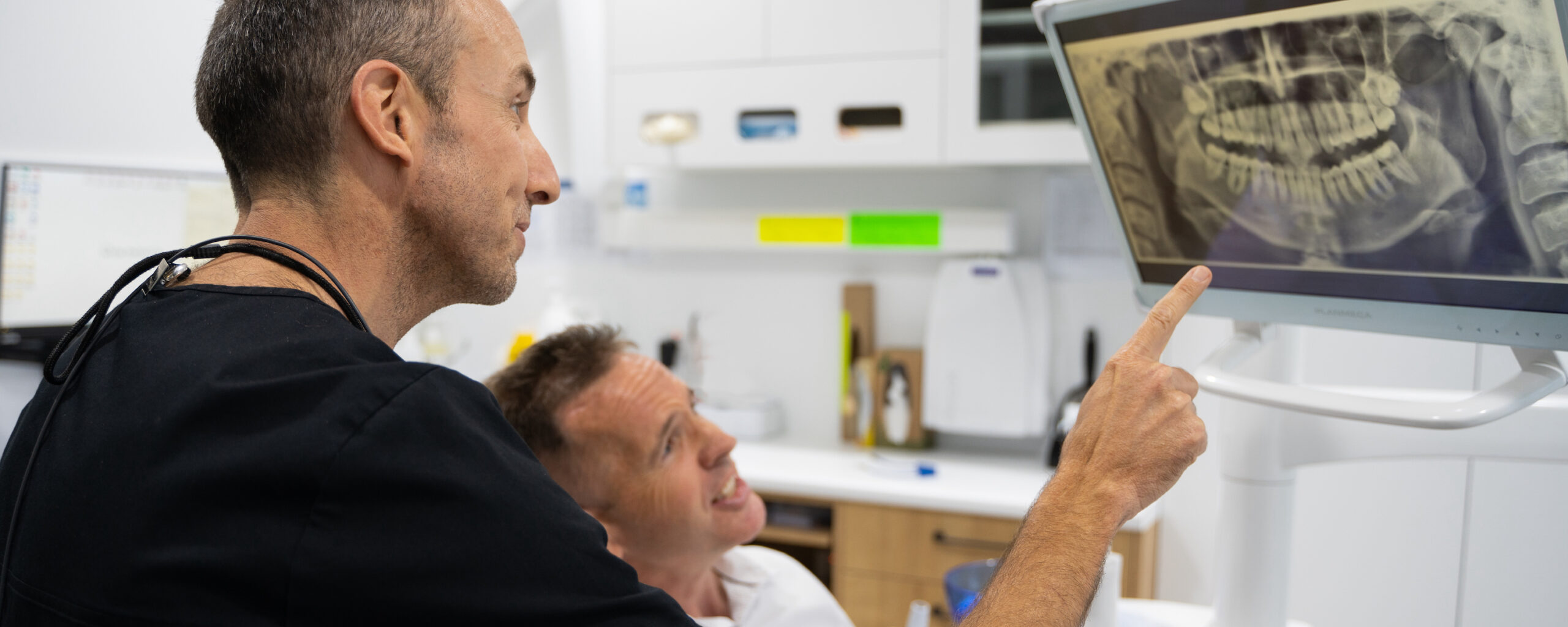 Dentist Dr Nick White reviewing an x-ray with a patient. The x-ray shows two impacted wisdom teeth