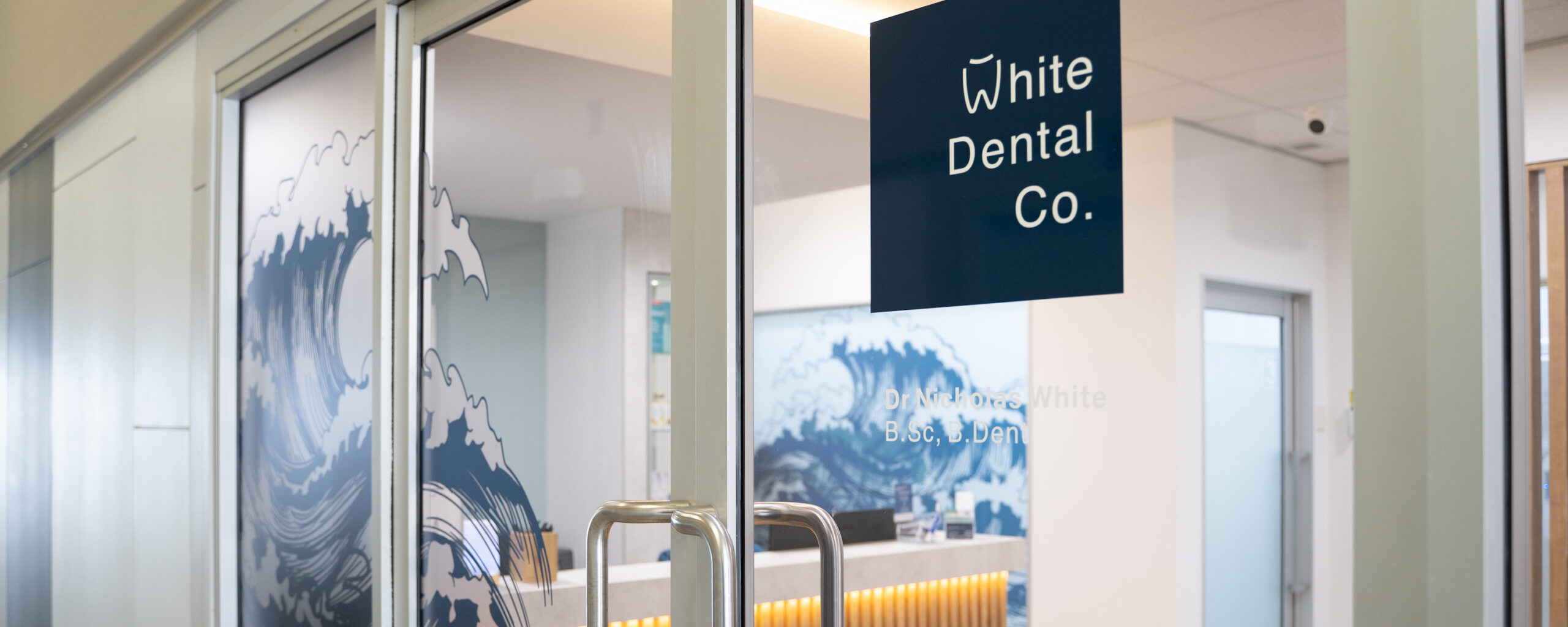 The front entrance of White Dental Co. features painted Japanese waves on the windows
